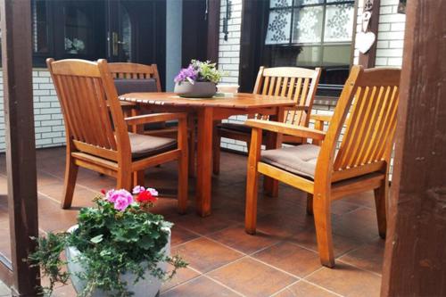 einen Holztisch mit vier Stühlen und einen Tisch mit Blumen in der Unterkunft Zimmervermietung M&R Bertuch in Jüterbog