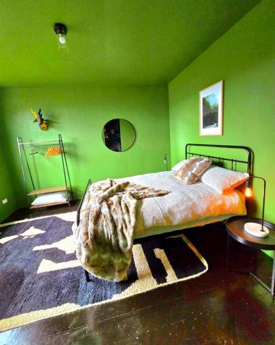 a bedroom with green walls and a bed with a blanket at Nordic Noir Cabin in Queenstown