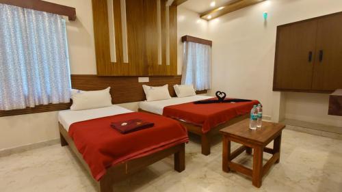 a room with two beds and a table at Mount Coco Resort Yercaud in Yercaud
