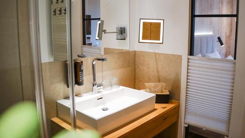 a bathroom with a white sink and a mirror at Hotel Leinsweiler Hof in Leinsweiler