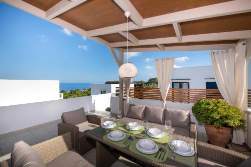 a patio with a table and chairs on a balcony at Outstanding Apartment in an Unique Aegean Inspired Settlement in Agia Triada