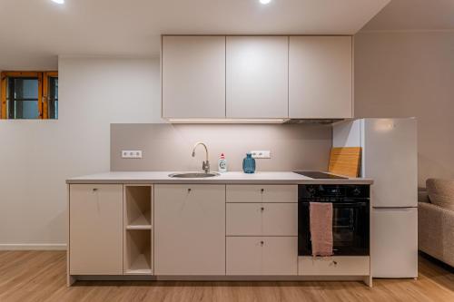 a kitchen with white cabinets and a sink at Komandandi Smart Stay City Center Apartments in Kuressaare