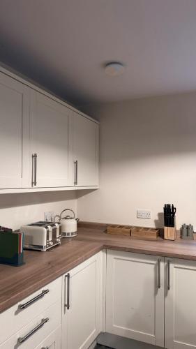 a kitchen with white cabinets and wooden counter tops at Superb Spacious Farm House in Henley on Thames
