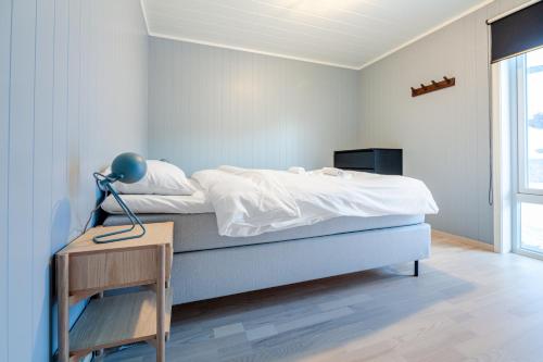 a bedroom with a bed and a table with a lamp at Seaside Apartment in Lofoten - Sea Views in Ballstad