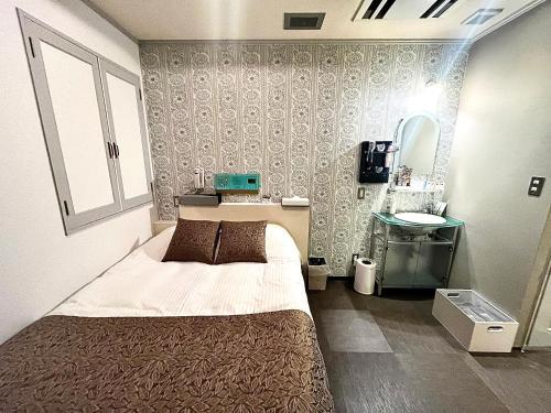 a small bedroom with a bed and a sink at Hotel U in Tokyo