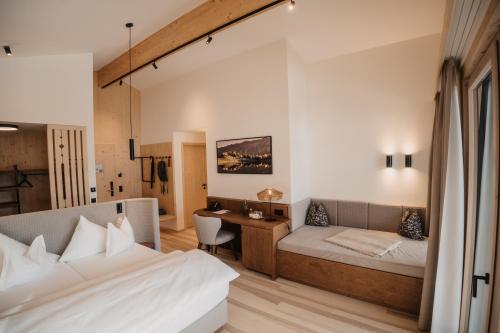 a bedroom with a bed and a desk in it at Hotel Neubergerhof in Filzmoos