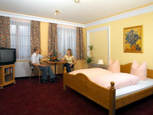 2 personnes assises à une table dans une chambre d'hôtel dans l'établissement Oldtimer Motel Pack, à Unterauerling