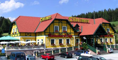 un bâtiment jaune et rouge avec des voitures garées dans un parking dans l'établissement Oldtimer Motel Pack, à Unterauerling