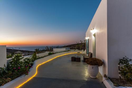 a pathway leading to a white building with a sunset at Argo-Milos in Adamas