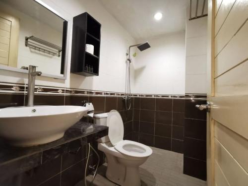 a bathroom with a sink and a toilet and a mirror at Watermelon Hotel in Miri