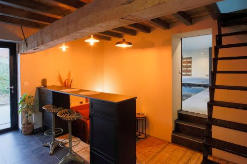 a room with an orange wall with a desk and stools at Cabanon à la FERME1802 in Sainghin-en-Mélantois