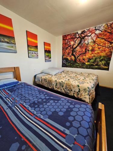 a bedroom with two beds and paintings on the wall at El valle in Copiapó