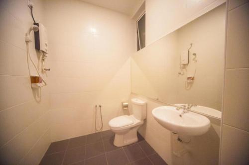 a white bathroom with a toilet and a sink at MD Boutique Hotel in Kampar