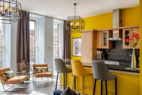 a kitchen with yellow walls and a table and chairs at Royal Mile Apartments by Joivy in Edinburgh