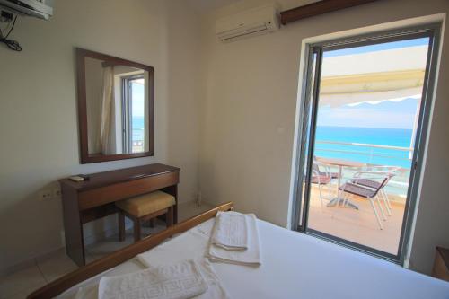 a bedroom with a bed and a mirror and a balcony at Platis-Gialos apartments in Loutsa