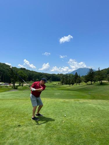 a man swinging a golf club on a golf course at Elan Villa Nojiri in Shinano