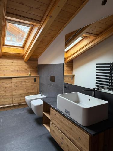 a bathroom with two sinks and a toilet and a window at Bormio Urban Attic in Bormio