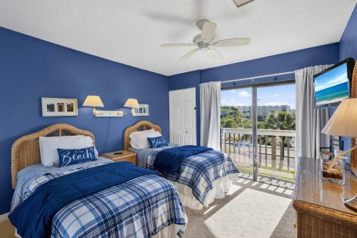 two beds in a blue bedroom with a balcony at Coastal Lakehouse Condo on Siesta Key Public Beach in Sarasota