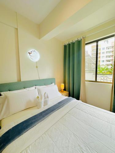 a bedroom with a large white bed with a window at POOLVIEW 2 bedrooms unit in Davao City