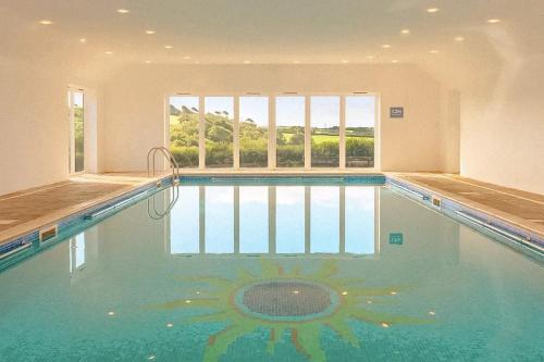 a swimming pool in a house with a large window at Tredethick Farm Cottages in Lostwithiel
