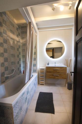 a bathroom with a tub and a sink and a mirror at Les Nuits du Pastelier in Teulat