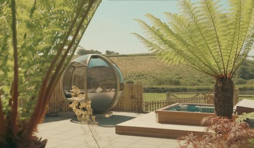 a circular pool in a garden with a palm tree at Tredethick Farm Cottages in Lostwithiel