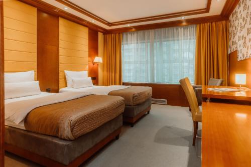 a hotel room with two beds and a desk at Garni Hotel Aleksandar in Novi Sad