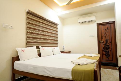 a bedroom with a bed with white sheets and a window at Thai Residency - Opp to Bus Stand in Dhārāpuram