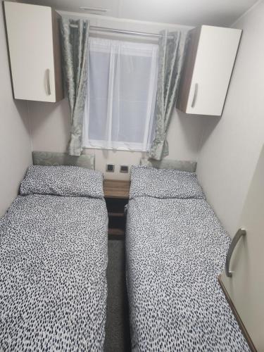 two beds in a small room with a window at Sam's Caravan Hire Coastfield Holiday Village Ingoldmells in Ingoldmells