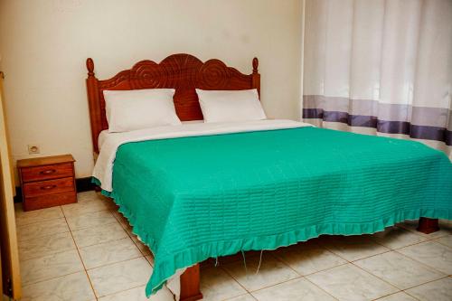 a bedroom with a large bed with a green comforter at Welcome Inn Guest house in Kigali