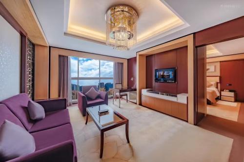 a living room with purple furniture and a chandelier at Dingyi Hotel in Heilinpu