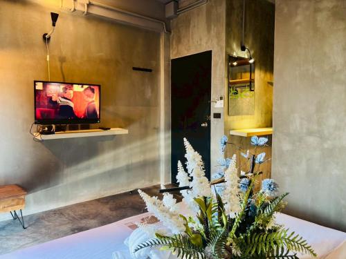 a room with a tv and a table with a plant at Bangkok Phattanakan32 guest house in Bangkok