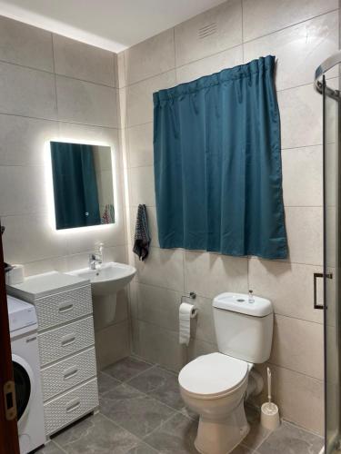 a bathroom with a toilet and a blue shower curtain at Xagħra Lodge in Xagħra