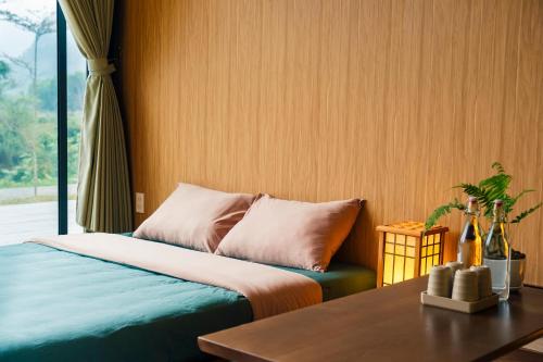 a bedroom with a bed and a table and a window at Blue Diamond Retreat in Vực Trô