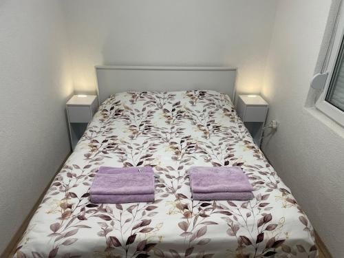 a bedroom with a bed with two purple towels on it at Vila Hristov in Delčevo