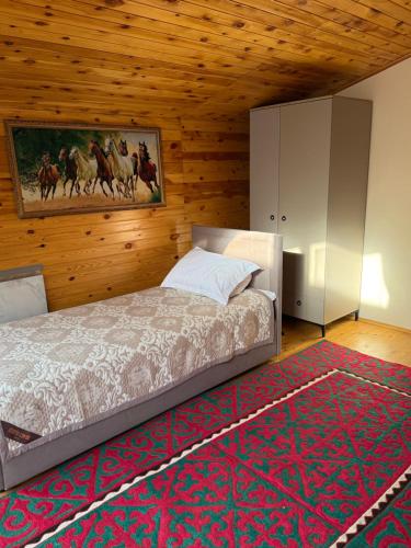 a bedroom with a bed and a painting on the wall at Ala-Archa Mountain House in Vorontsovskoye
