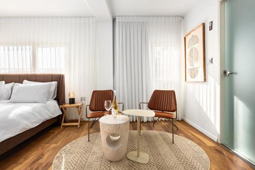 a bedroom with a bed and two chairs and a table at One Apartments TLV in Tel Aviv