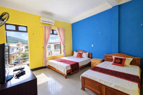 two beds in a room with blue and yellow walls at Thuỳ Dương Hotel Cao Bằng in Bảo Lạc