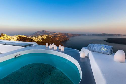 a blue swimming pool with a view of the water at Pura Vida Villa in Imerovigli