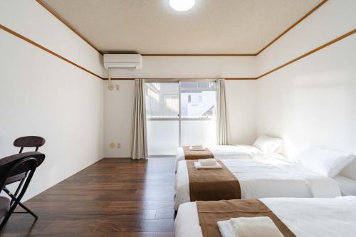 a hotel room with two beds and a window at Kasuga Good Place House in Kasugabaru