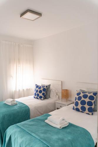 a bedroom with two beds with blue and white pillows at Los Bungalows Del Arenal in Jávea