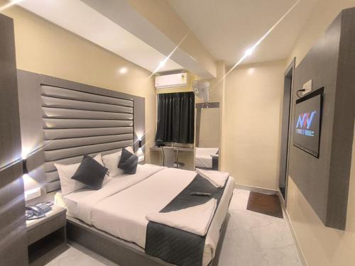 a bedroom with a large bed and a television at Sahara Inn in Mumbai