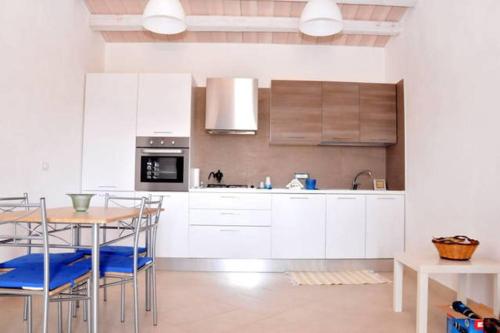 a kitchen with white cabinets and a table and chairs at Villa Ilaria in Marzamemi