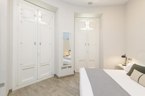 a white bedroom with a bed and a closet at Apartamentos Calle Larios in Málaga