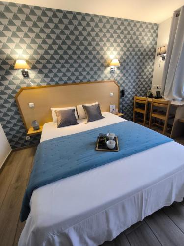a hotel room with a large bed with a tray on it at Hôtel Le Laury's-hôtel calme proche de Rodez avec parking privé gratuit-Arrivée après 20h possible via borne automatique in Onet le Château