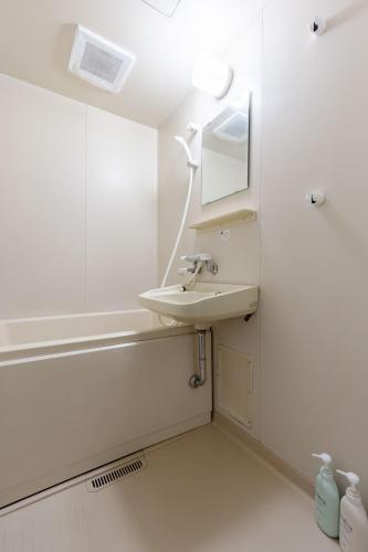 a bathroom with a sink and a bath tub at Kasuga Good Place House in Kasugabaru