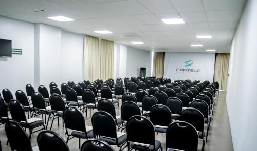 a conference room with black chairs and a screen at Fratele Business Hotel in Patos de Minas
