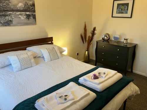 a bedroom with a bed with towels and a dresser at Lavender Cottage in Thirsk