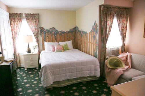 a bedroom with a bed and a couch and windows at The Ocean Plaza Hotel in Ocean Grove