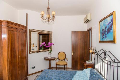 a bedroom with a bed and a mirror and a chair at Hotel Miramare in Lignano Sabbiadoro